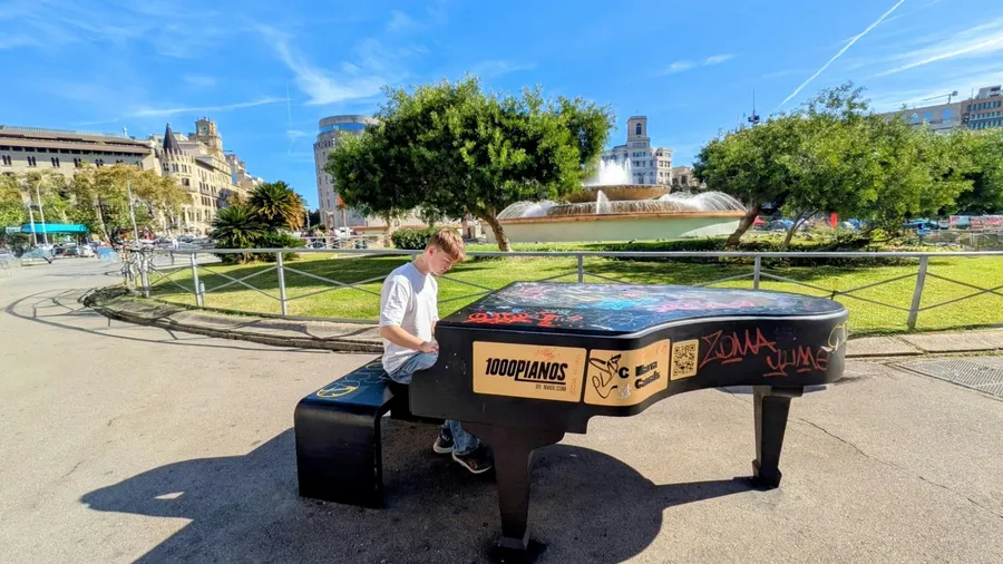 Jack Morgan playing a public grand piano outdoors on a sunny day